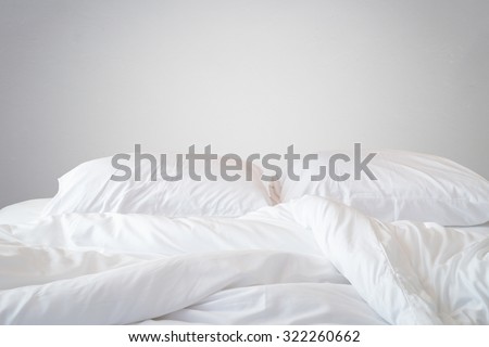 Close up white bedding sheets and pillow on natural stone wall room background, Messy bed concept