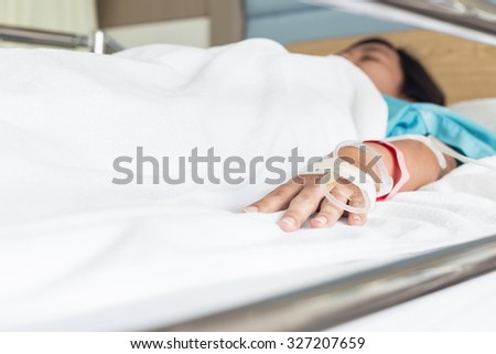 Close up hand of female patient with IV drip needle piercing in hospital room