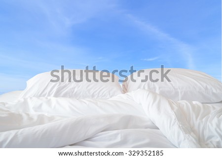 Close up white bedding sheets and pillow on view of sky background