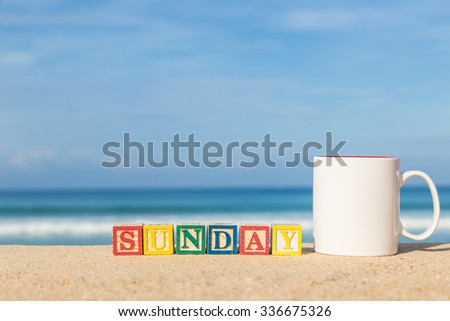 word SUNDAY in colorful alphabet blocks and coffee cup on tropical beach, Phuket Thailand