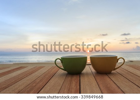 Close up coffee cup on wood table and view of sunset or sunrise background