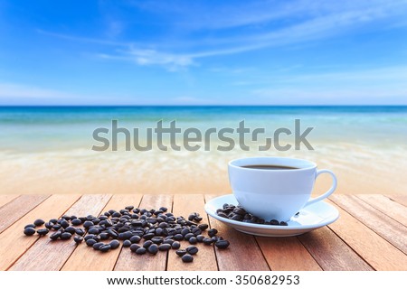 Close up white coffee cup and coffee beans on wood table and view of sunset or sunrise background
