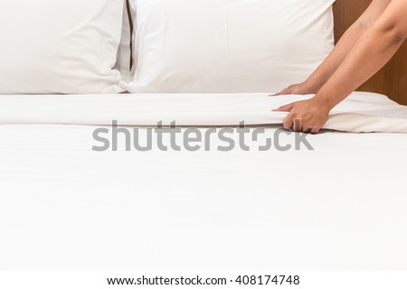 Close up hand set up white bed sheet in hotel room