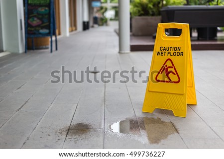 Yellow wet floor warning sign on the floor in hotel corridor