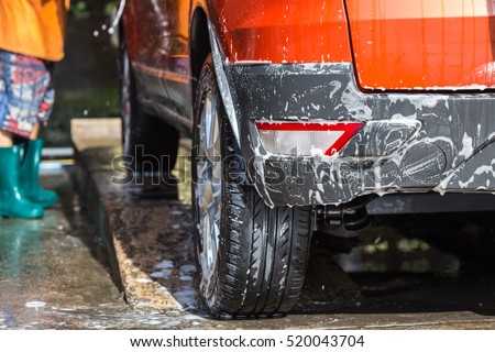 A man spraying pressure washer for car wash in car care shop. Focus on backside of car