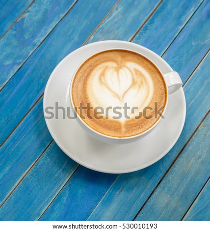 Top view hot latte coffee in white cup on blue vintage wooden table background