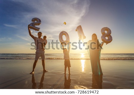 Silhouette of family holding number balloon 2018 on the beach at the sunset time. Outdoor, family and new year concept.