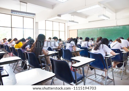 blur focus.back view abstract background of examination room with undergraduate students inside. university student in uniform sitting on lecture chair taking final exam or study in classroom.