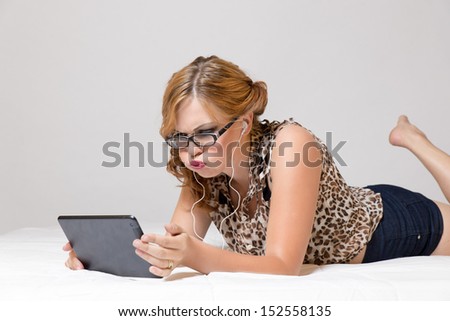 Reading tablet, exasperated with the news she is reading, with ear-buds