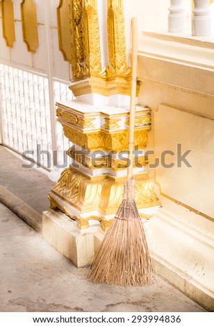 Old coconut leaf broom or besom leaning on the temple wall in the evening. People used broom to clean their temple for being peace.