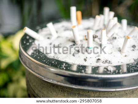 Background of Blurry cigarette butts in the ashtray dirty. Smoking people will get lung cancer and more disease soon.