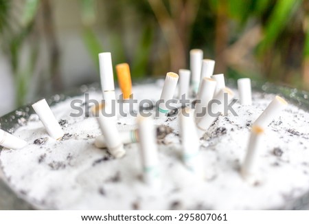 Background of Blurry cigarette butts in the ashtray dirty. Smoking people will get lung cancer and more disease soon.