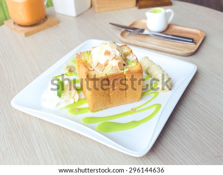 Ice cream on honey toast topped with Thai Pandan Custard on wooden table.