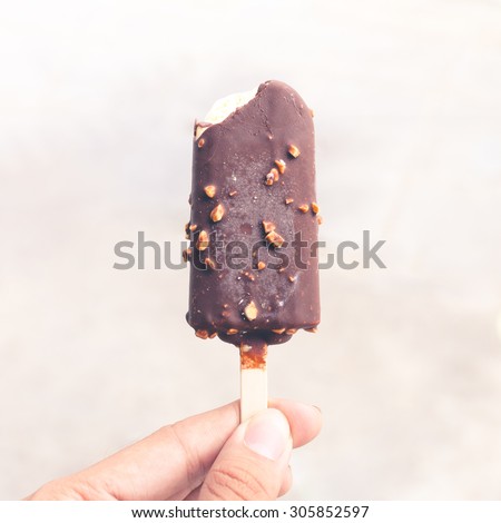 Hand holds bitten chocolate vanilla ice cream. Vintage tone