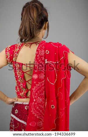 Rear view of a young Indian woman standing with her arms akimbo