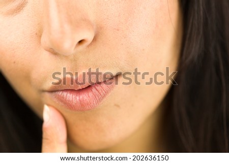 Extreme close-up of a young woman day dreaming with finger on chin