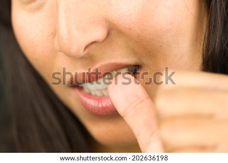Extreme close-up of a young woman biting her nails