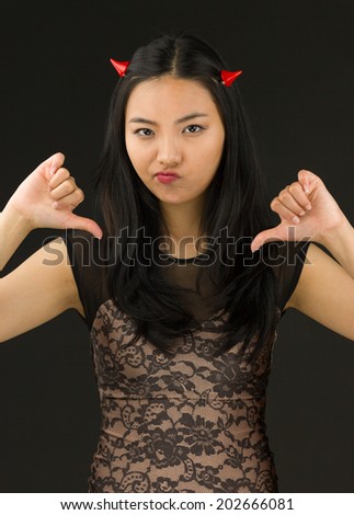 Asian young woman dressed up as an devil showing thumbs down sign from both hands