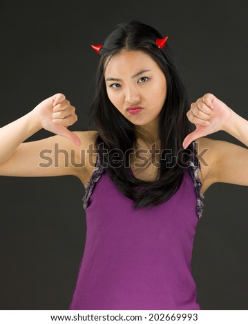 Devil side of a young Asian woman showing thumbs down sign with both hands
