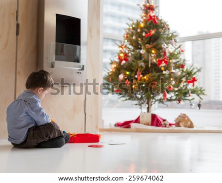Side profile of a little boy playing with toy car and Christmas tree in the background