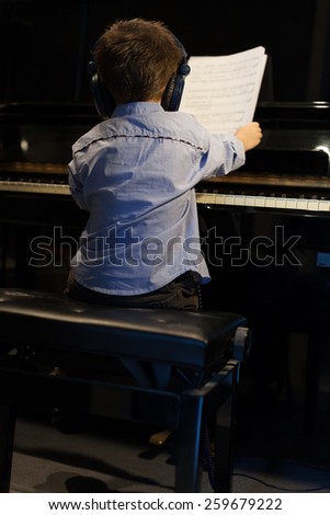 Rear view of a little boy learning piano