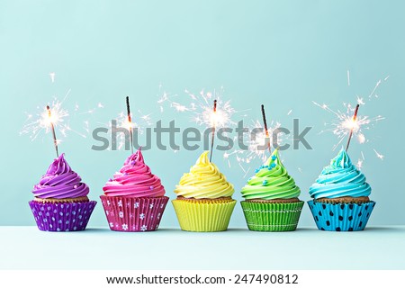 Row of colorful cupcakes with sparklers