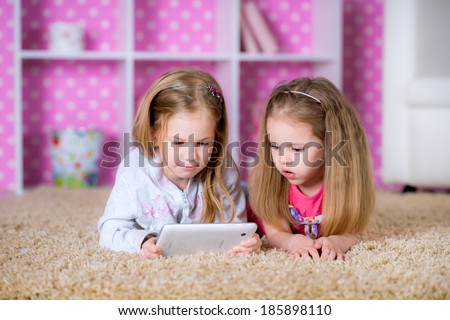 Cute girls playing on a tablet PC computing device - laying on the floor