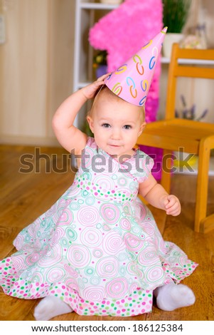 Cute funny little kid in first birthday with colored balloons in the room