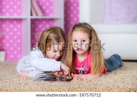 Little kids playing on a tablet computing device - laying on the floor in the room