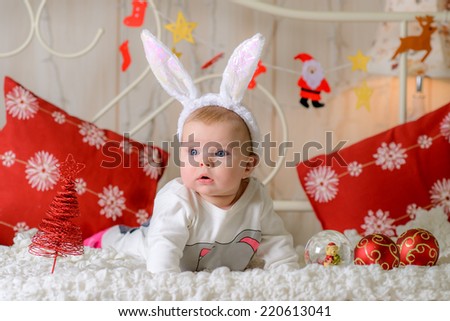 little cute girl near the Christmas  illuminations  at home on the bed in rabbit ears
