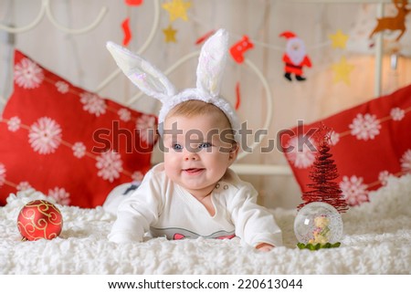 little girl near the Christmas  illuminations  at home on the bed in bunny costume