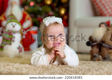 New Year\'s Concept. Adorable little girl near a Christmas tree with presents laughs. new year fun game