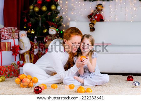 happy mother and daughter near a christmas gifts on the floor of fruit