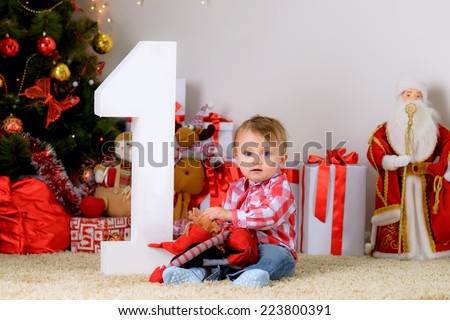 happy child on the floor under the tree with a new toy is celebrating its first Christmas and New Year