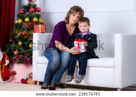 happy family on a white couch Christmas morning with gifts at the Christmas tree fun red white decorations, gifts