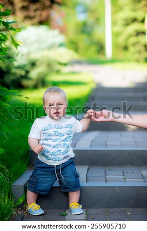 little boy sitting on the steps and keeps mom \'s hand