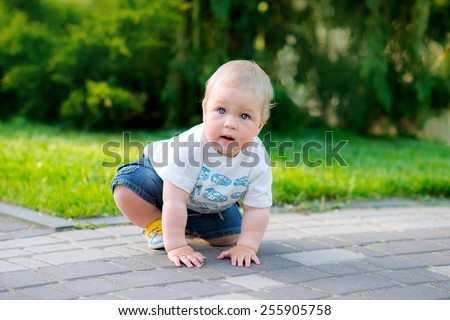 Happy child is sitting in the spring park crawling on all fours