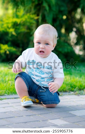 cute baby boy sitting in the spring park happy learns to stand up on your feet