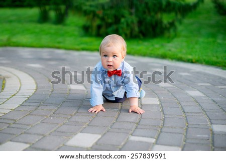 little boy in the park in jeans and a blue shirt in a red bow tie fun playing