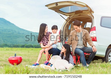 drive in the vacations family; asian family are happy sitting in the open trunk of a car;  travel nature trip.