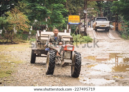 VANG VIENG, LAOS - OCT 24: An unidentified man driving tractor on a rural road on oct 24, 2014, in Vang Vieng, Laos. Vang Vieng is a tourism-oriented town in Laos, lies on the Nam Song river.