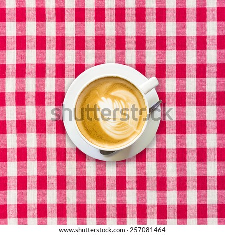 cappuccino coffee on white and red checkered background close up