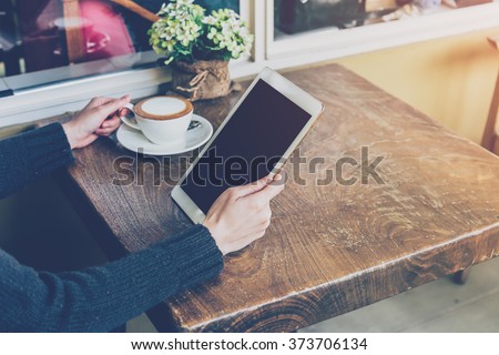Close up hand woman using tablet in coffee shop with vintage tone.
