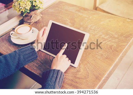 woman play tablet computer in coffee shop with vintage tone.