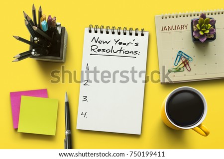 New Year resolutions, goals or action plan concept. Notebook on office table with calendar, coffee, plant and stationery. Flat lay (top view) notepad for input copy or text on yellow background.