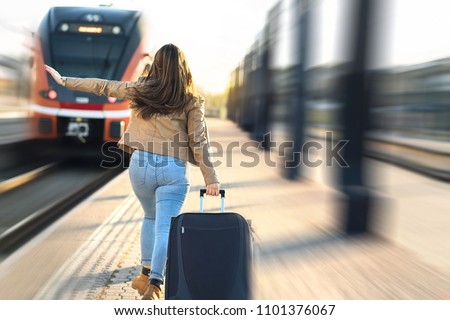 Late from train. Woman running and chasing the leaving train in station. Waving hand and rushing to get on. Female tourist with stress pulling suitcase in platform.