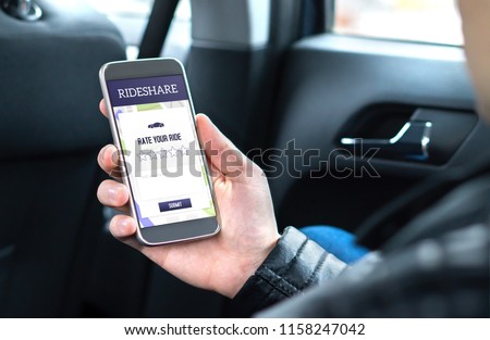 Ride share customer and passenger sitting in the backseat of a car while using the rideshare application in smartphone to give rating to the driver. Commuter and rider giving review in phone taxi app.