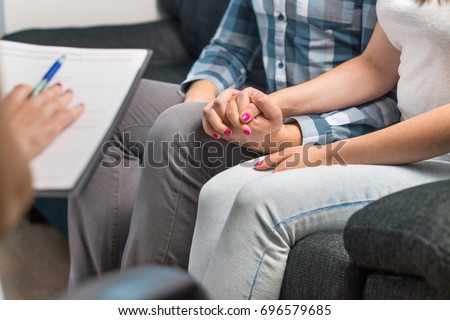 Couples therapy or marriage counseling. Man and woman holding hands on couch during a psychotherapy session. Psychologist, counselor, therapist, psychiatrist or relationship consultant giving advice.