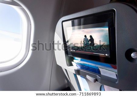 Watching movie on an airplane touch screen. Imaginary film playing on a video player in monitor during long flight. Entertainment service system in aircraft.