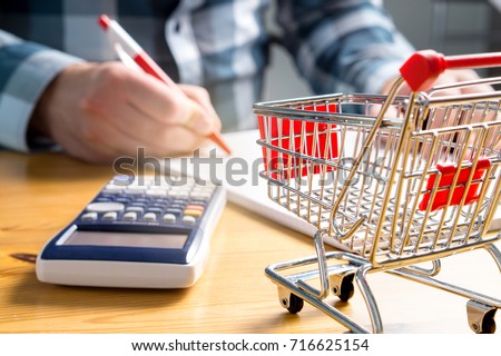 Rising food and grocery store prices and expensive daily consumer goods concept. Man counting food money with pen, paper and calculator at home. Budget of disadvantaged and low income family.